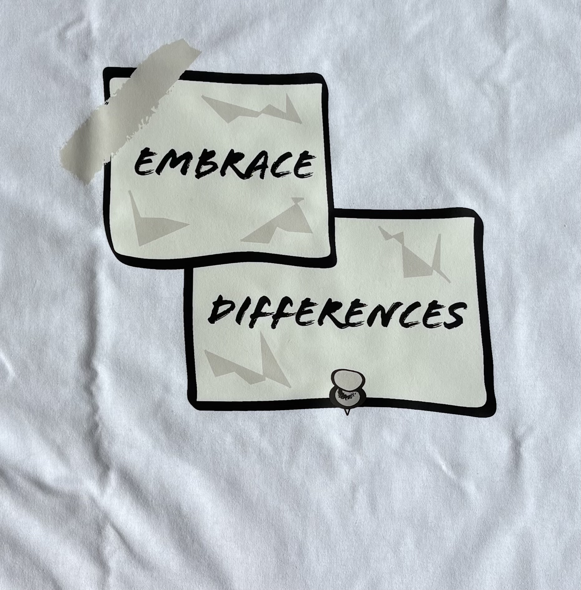 Close-up of the actual black Embrace Differences paper print on a white T-shirt
